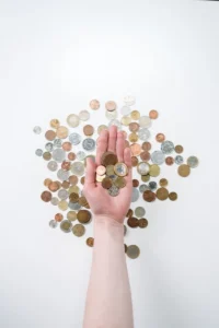Hand holding coins over scattered coins