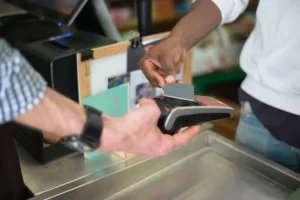 Customer tapping a blank card on a payment terminal at a shop counter