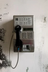 Old metal coin payphone mounted on a wall