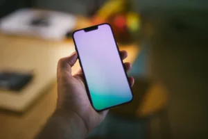 Hand holding a smartphone with a plain coloured screen