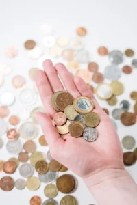 Hand holding a small pile of mixed coins over a table of coins