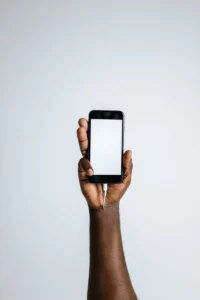Hand holding a smartphone with a blank white screen and a charging cable