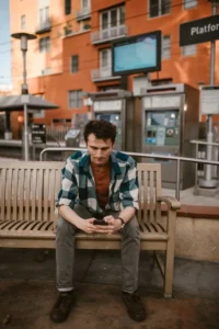 Man sitting on a bench outdoors looking at his phone