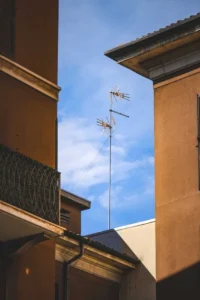 Television antennas on a tall pole between buildings against the sky