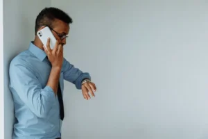 Man holding a phone to his ear while checking his watch