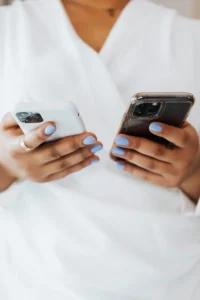 Person holding two smartphones, one in each hand