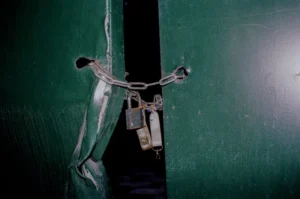 Green metal gate chained shut with a padlock at night