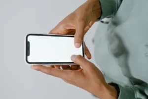 Two hands holding a smartphone with a blank white screen