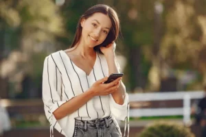 Woman outdoors smiling while holding a phone